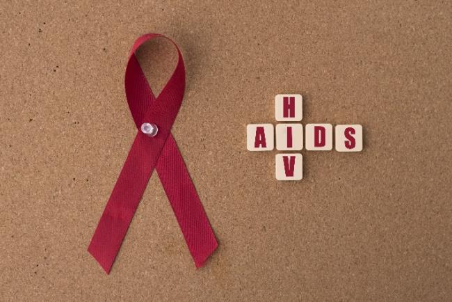 לוח ועליו סרט המודעות לאיידס, ואיות של מחלת האיידס ונגיף ה-HIV